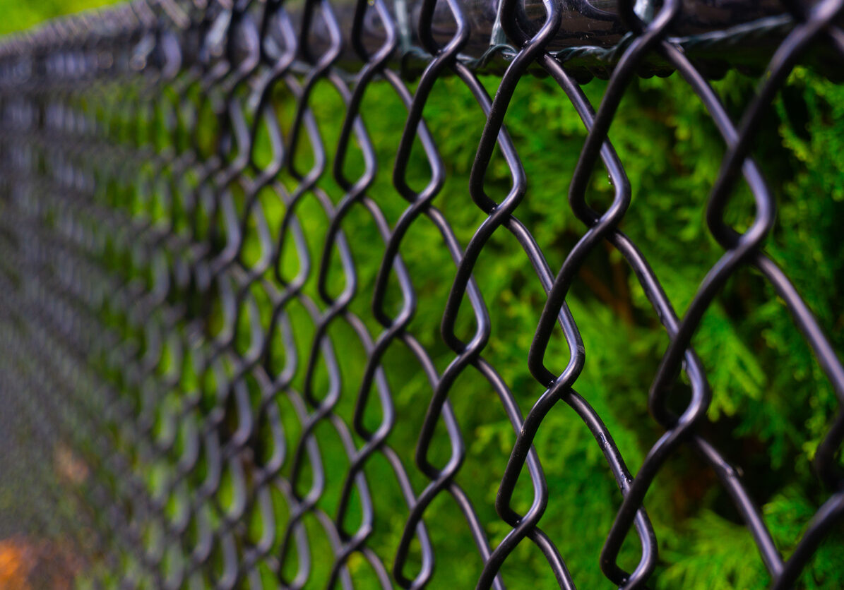A black chain link fence photographed from a creative perspective to give the image depth.
